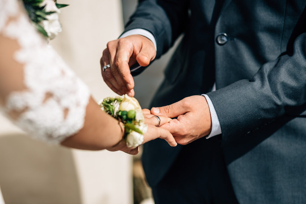 Der Bräutigam steckt der Braut den Ehering an den Finger.