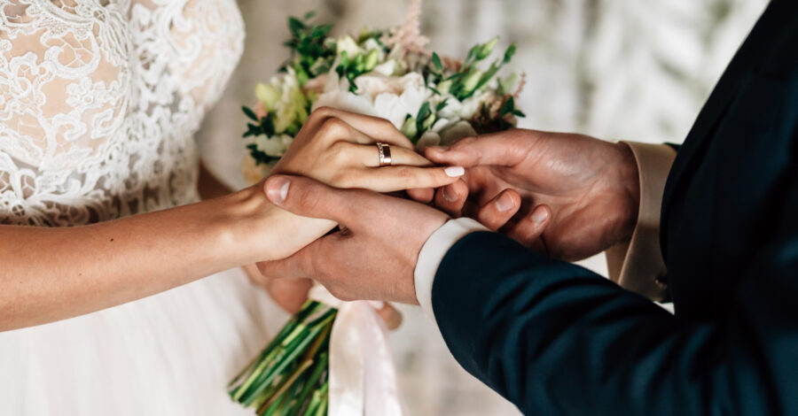 Bräutigam steckt der Braut Ehering und Verlobungsring an