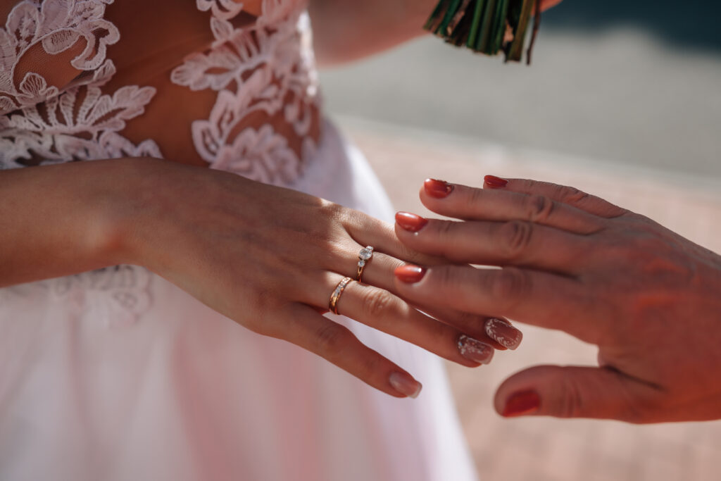 Die Braut trägt den Verlobungsring am Mittelfinger und den Trauring am Ringfinger